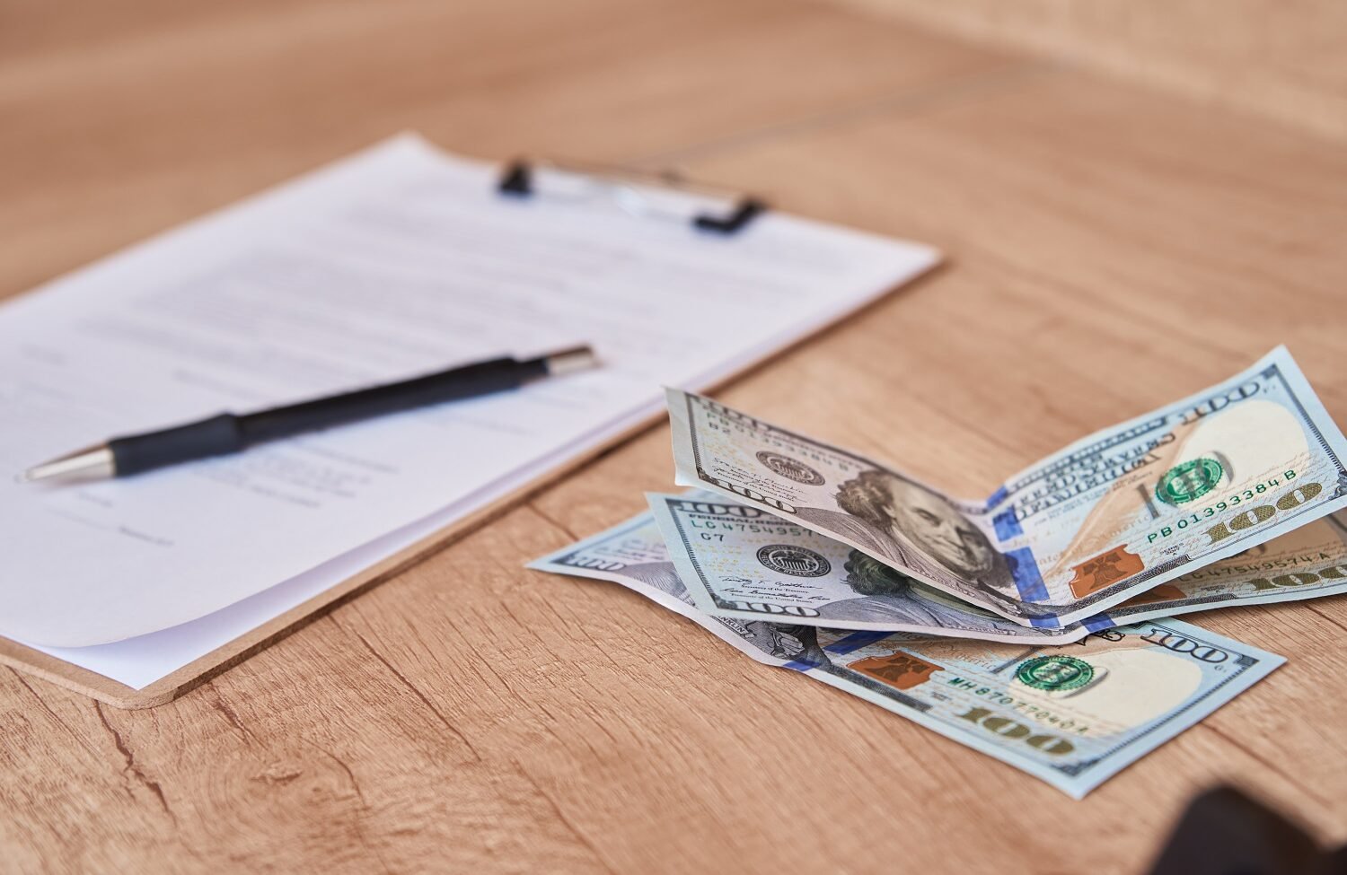 document, pen and dollar bills on table, close up